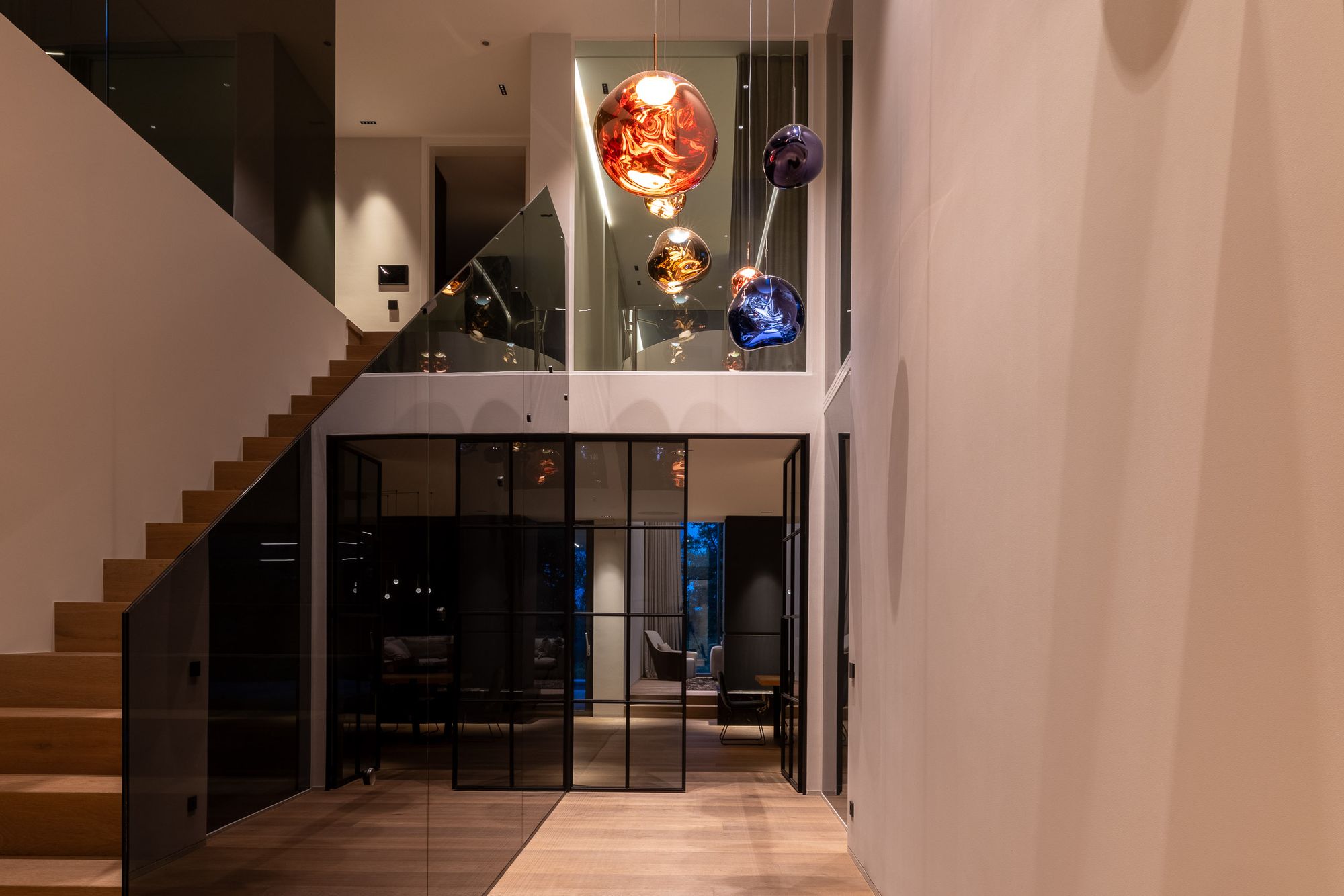Treppe und Luftraum mit skulpturalen Designleuchten am Abend